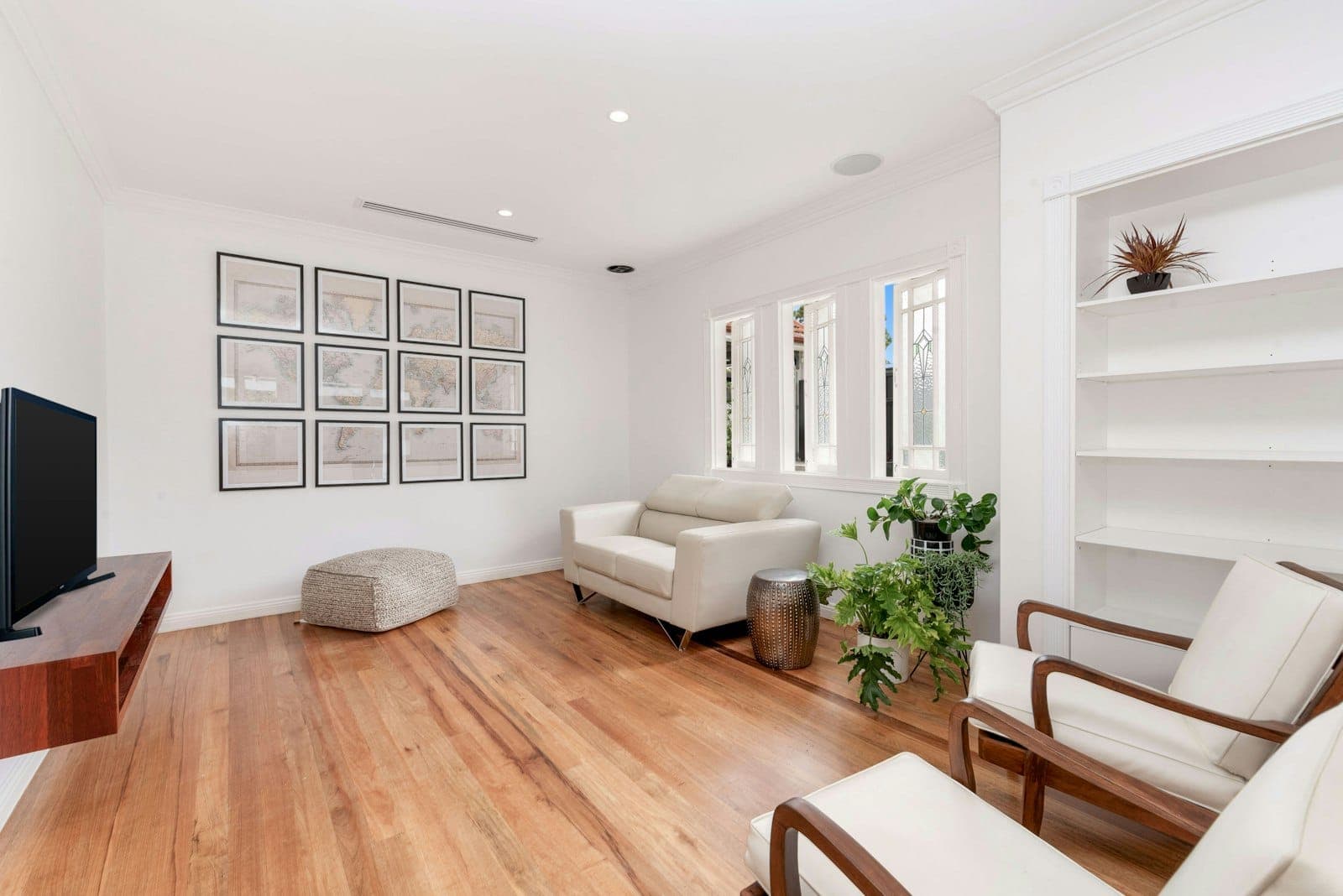 Bright, freshly painted living room with crisp white walls, hardwood floors, and a gallery wall