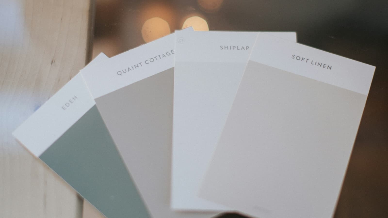 Large-format paint swatches fanned out in natural daylight on a wood surface